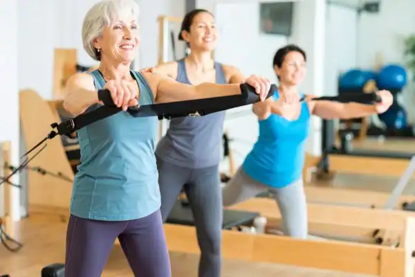 Toning Arms After 60: Empowering Womens Fitness Through Effective Weight Training 2 older woman doing weight training Ayr and resistance in the gym to tone upper arms